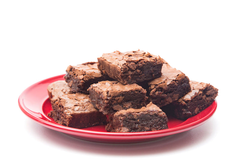 A plate of freshly baked brownies stacked on a red dish against a white background.