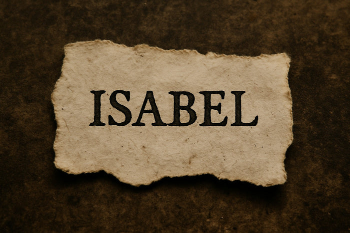 Torn piece of aged parchment bearing the name “ISABEL” in bold black letters, set against a dark, textured brown background.