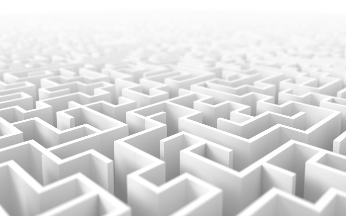 Close-up of a white maze with intricate pathways on a light gray background.