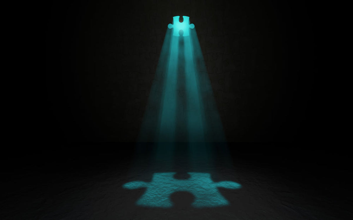 Jigsaw puzzle piece with glowing blue light in a dark room.